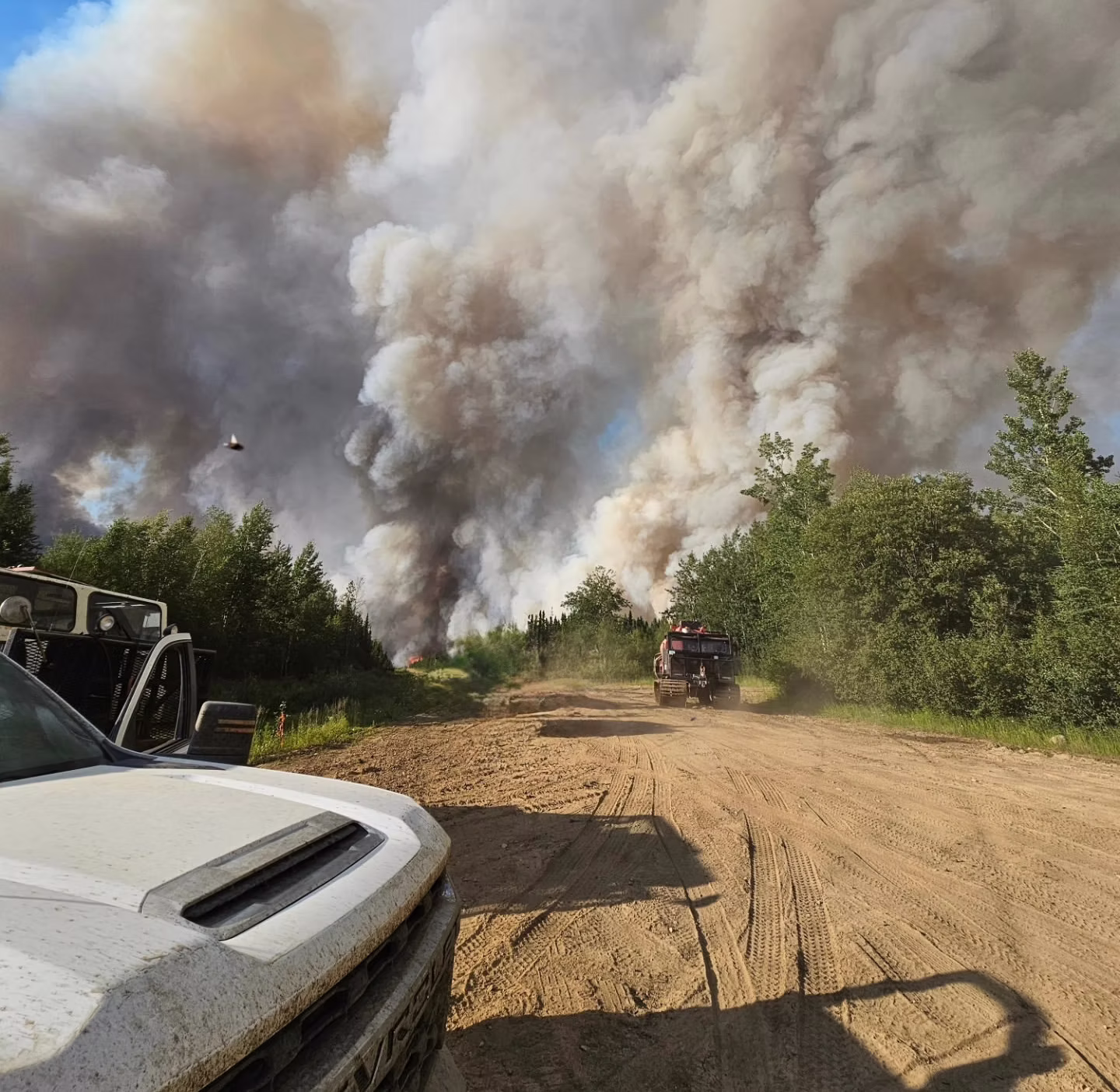 SRC field truck in the foreground with a large wildfire smoke column rising behind it